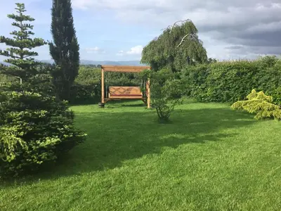 a wooden bench sitting in a green yard at Woodcockfaulds House in Stirling