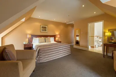 a bedroom with a bed and a couch and a chair at Sherbrooke Castle Hotel in Glasgow