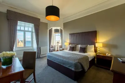 a hotel room with a bed and a desk and a table sidx sidx at Sherbrooke Castle Hotel in Glasgow