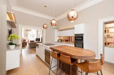 a kitchen with white cabinets and a wooden table at JOIVY Ultra Luxe Home near Princes Street in Edinburgh