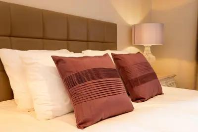 a bed with two brown pillows and white pillows at JOIVY Gorgeous Flat near The Scotland Gallery in Edinburgh