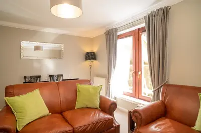 a living room with a brown leather couch and a window at JOIVY Gorgeous Flat near The Scotland Gallery in Edinburgh