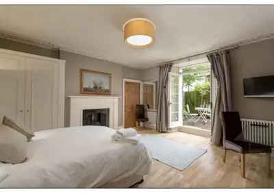 a bedroom with a white bed and a fireplace at JOIVY Boutique Apt with Patio in New Town in Edinburgh