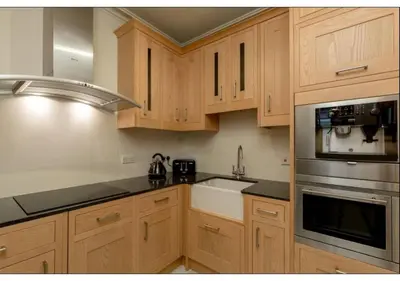 a kitchen with wooden cabinets and stainless steel appliances at JOIVY Boutique Apt with Patio in New Town in Edinburgh