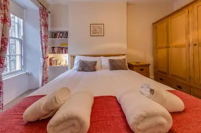 a bedroom with a large white bed with a red rug at JOIVY Stylish Apt in Trendy New Town Location in Edinburgh
