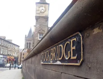a sign on the side of a wall with a clock tower at JOIVY Stylish Apt in Trendy New Town Location in Edinburgh