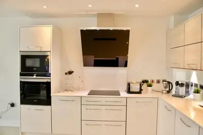 a kitchen with white cabinets and black appliances at Luxurious Central Edinburgh Apartment - Sleeps 6 in Edinburgh