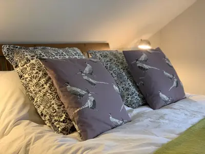 a bed with two pillows on top of it at Charming cottage with loch and hill views nr Edinburgh in Cobbinshaw