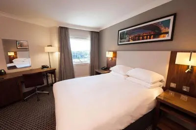 a hotel room with a large white bed and a desk at Doubletree By Hilton Glasgow Strathclyde in Bellshill