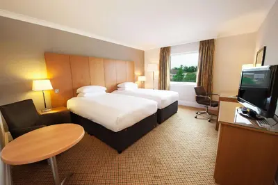 a hotel room with a bed and a desk and a television at Doubletree By Hilton Glasgow Strathclyde in Bellshill