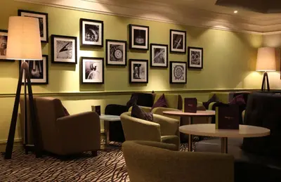 a waiting room with chairs and tables and pictures on the wall at Doubletree By Hilton Glasgow Strathclyde in Bellshill