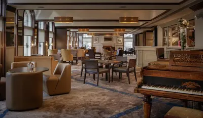 a restaurant with a piano and tables and chairs at Glasgow Grosvenor Hotel in Glasgow