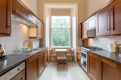 a kitchen with wooden cabinets and a table and a window at JOIVY Spacious Apt in New Town Prime Location in Edinburgh