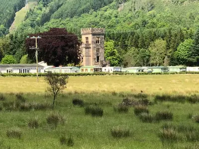 an old building in a field with a train at Brookwood Sea View 14 in Dunoon