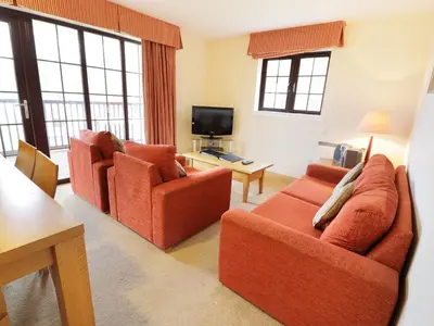 a living room with two orange chairs and a television at Savita Cottage in Girvan