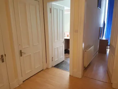 a hallway with an open white door and a table at Bentinck Street Ground Floor Apartment in Glasgow