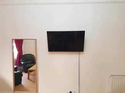 a flat screen tv on top of a white wall at Bentinck Street Ground Floor Apartment in Glasgow