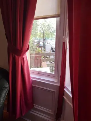 a window with a red curtain in a room at Bentinck Street Ground Floor Apartment in Glasgow