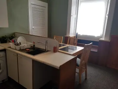 a kitchen with a sink and a counter with chairs at Bentinck Street Ground Floor Apartment in Glasgow
