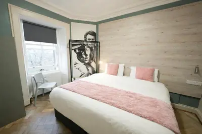 a bedroom with a large bed with pink pillows at Revolver Edinburgh in Edinburgh