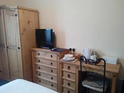 a bedroom with a wooden dresser with a television on it at Homestay, Number 29, Dunollie in Oban