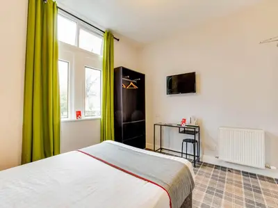 a bedroom with a bed with green curtains and a window at Lost Guest House Stirling in Stirling