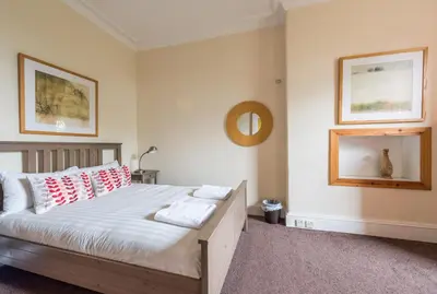 a bedroom with a bed with red and white pillows at 3 bed overlooking meadows park in Edinburgh