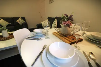 a dining room table with white plates and wine glasses at Signature - Glen Lee House in Glasgow