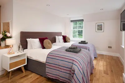 a bedroom with two beds and a desk and a window at Mill House Monzie in Crieff