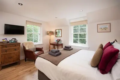 a bedroom with a large bed and a chair at Mill House Monzie in Crieff