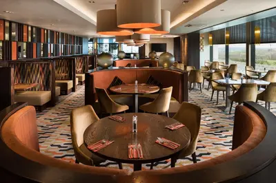 a restaurant with tables and chairs and a library at Radstone Hotel in Larkhall