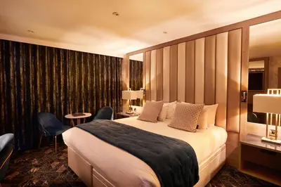 a hotel room with a large bed and chairs at Radstone Hotel in Larkhall