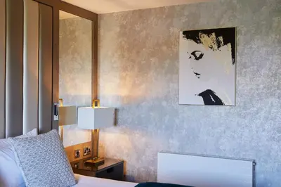 a bedroom with a bed and a picture on the wall at Radstone Hotel in Larkhall