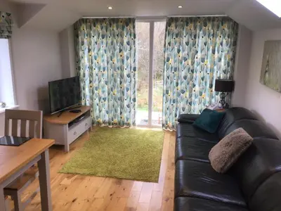 a living room with a black leather couch and a table at Burn View in Stronachlachar
