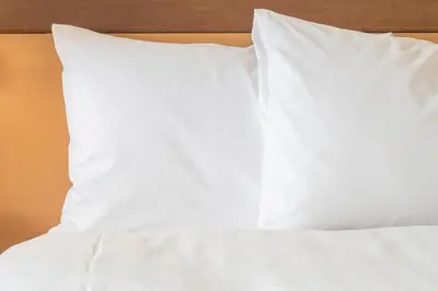 a bed with white sheets and pillows on it at Holiday Inn Express Strathclyde Park M74, Jct 5 by IHG in Motherwell