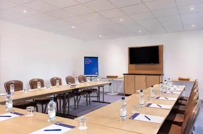 a conference room with tables and chairs and a screen at Holiday Inn Express Strathclyde Park M74, Jct 5 by IHG in Motherwell