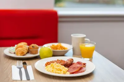 a table with two plates of breakfast food and orange juice at Holiday Inn Express Strathclyde Park M74, Jct 5 by IHG in Motherwell