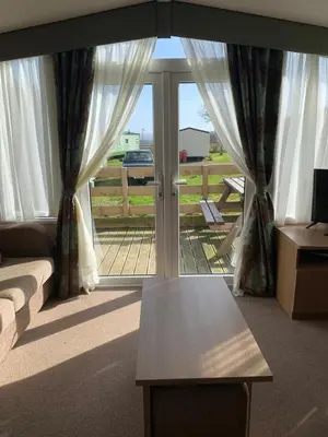 a living room with a couch and a glass door at Swift bordeaux 24 in Dunoon