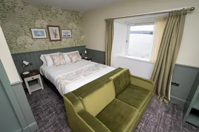 a bedroom with a bed and a window and a chair at Ardencaple Hotel by Greene King Inns in Helensburgh