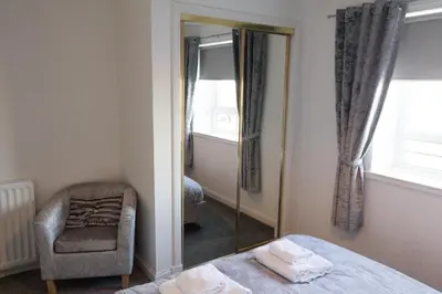 a bedroom with a mirror and a chair and a bed at No27 Ayr Beach - Coorie Doon Stays in Ayr
