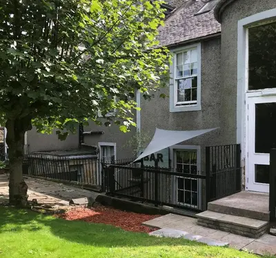 a house with a fence with a white umbrella on it at Ashtree House Hotel, Glasgow Airport & Paisley in Paisley