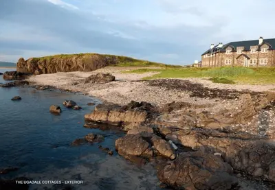 a house on top of a cliff next to the ocean at The Ugadale Hotel in Campbeltown
