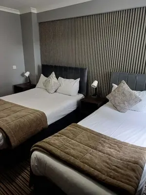 a hotel room with two beds and two lamps at Kings Park Hotel in Glasgow