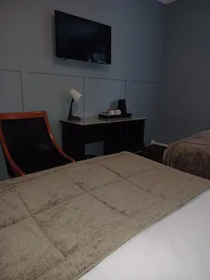 a bedroom with a bed and a desk with a television at Kings Park Hotel in Glasgow