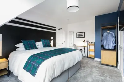 a bedroom with a large bed and a desk at Castle Park Guest House in Edinburgh