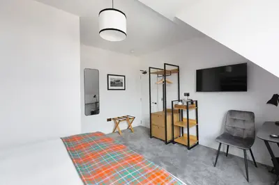 a room with a bed and a chair and a television at Castle Park Guest House in Edinburgh
