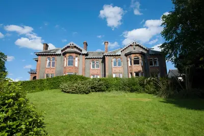 an old mansion on a hill with a green yard at Warriston Apartment at Holm Park in Moffat