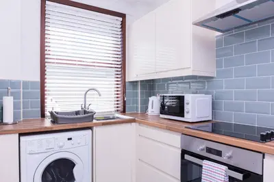 a kitchen with a washing machine and a microwave at Peebles House - Coorie Doon Apartments in Ayr