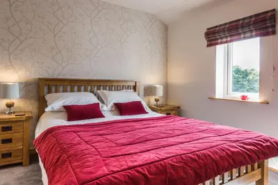 a bedroom with a large bed with a red blanket at Oakbank Farm in Lamlash