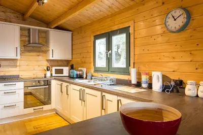 a kitchen with white cabinets and a clock on the wall at Oakbank Farm in Lamlash